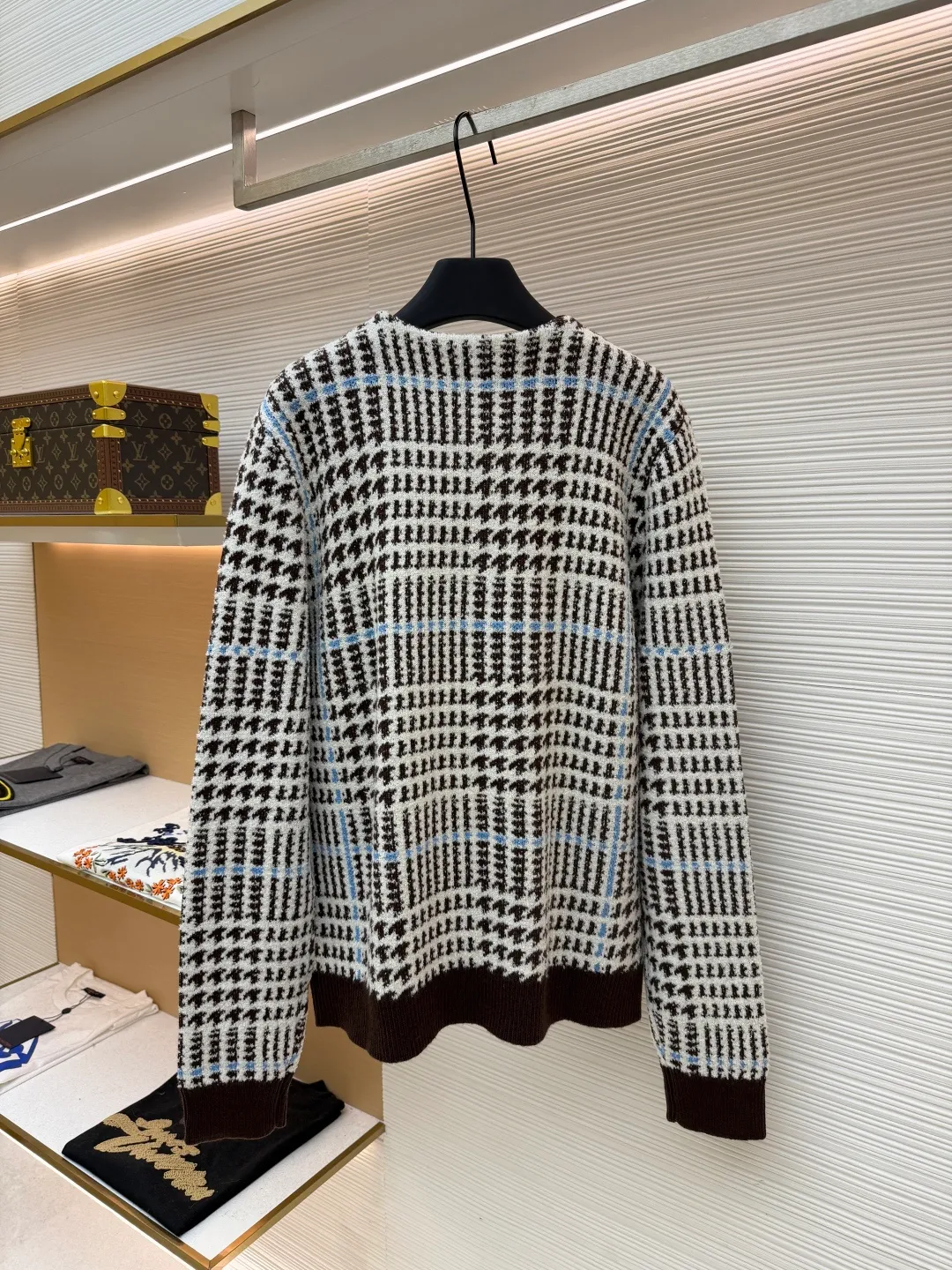 LOUIS VUITTON letter intarsia houndstooth knitted jacquard cardigan ●Original version: purchased and developed by 14743 ●Item number: 1681873-C00 ●Fabric: wool blended fabric ●Technology: jacquard knitting ●Color: black, white and blue ●Version: fitted version ●Weight: about 695 grams ●Size: S-M-L-XL ●Description: The main pattern of this cardigan is woven with full-width jacquard technology, using 69% sheep wool blended with 31% nylon yarn to interweave the houndstooth pattern with light blue line texture. At the same time, the brand logo elements are integrated into the body through intarsia technology, and the edges of the pattern are connected delicately and seamlessly. The collar, cuffs and hem are made of 100% sheep wool ribbed fabric, and are edged with double-needle seaming technology, which has both elasticity and shaping effect. The front placket is equipped with natural-textured buttons, and the side seam pockets use invisible stitching technology to blend naturally with the jacquard texture of the body. The overall shape is shaped through three-dimensional tailoring, and the shoulders are stitched with seamless stitching to ensure fit and comfort. The entire piece is finished with handcrafted details in an Italian workshop, showing the craftsmanship precision of high-quality knitted items. The overall wiring is straight and delicate, the fabric is comfortable and soft, and the color is consistent without color difference. It can be matched with the same style to create a fashionable look and control various occasions. Customized accessories, complete with three standards, same style for men and women!